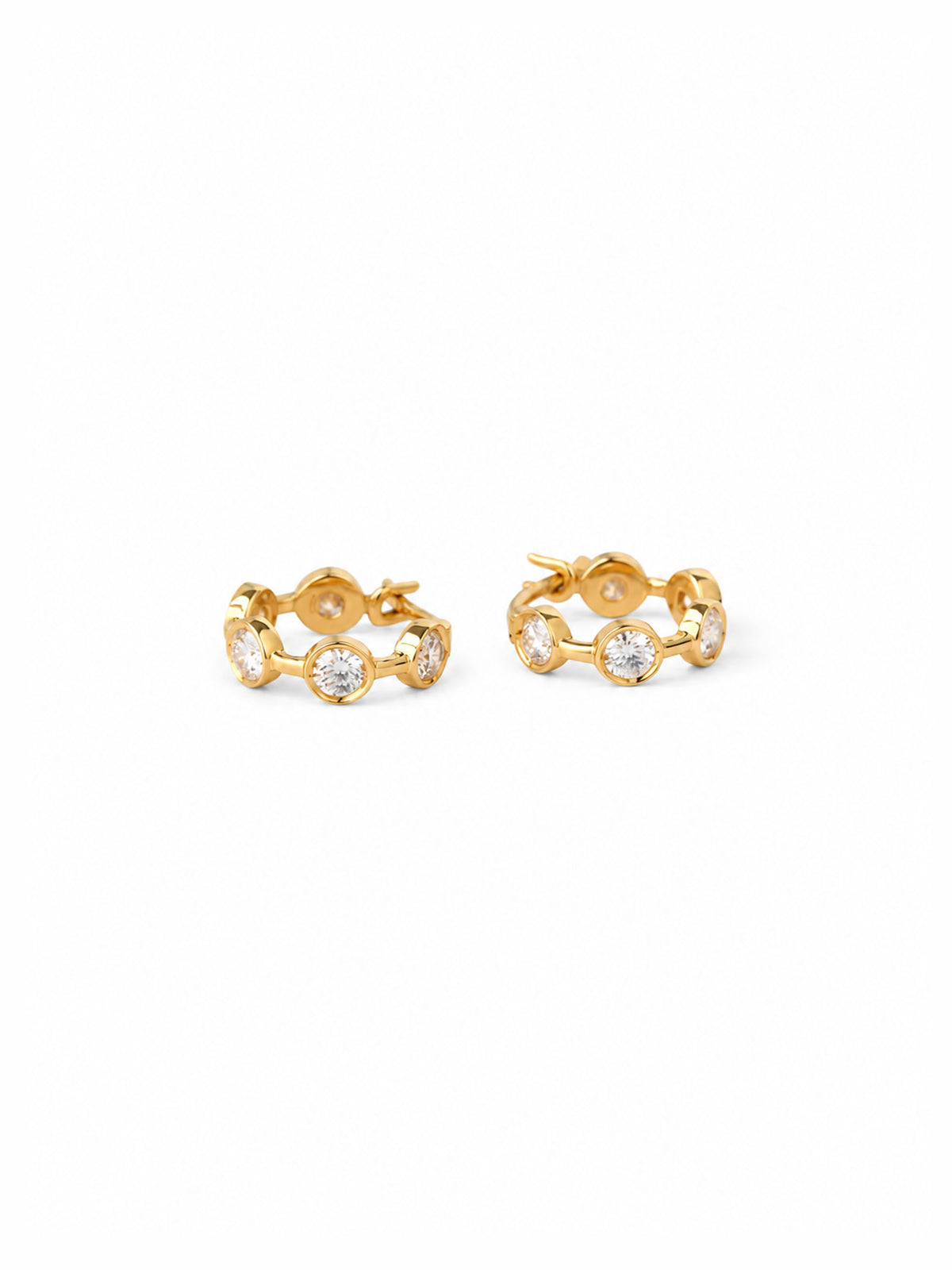 These 12 mm hoops translate the idea into 18-karat solid gold and brilliant diamonds, with the stones appearing almost like tiny drops of water caught along the curve of the earring.