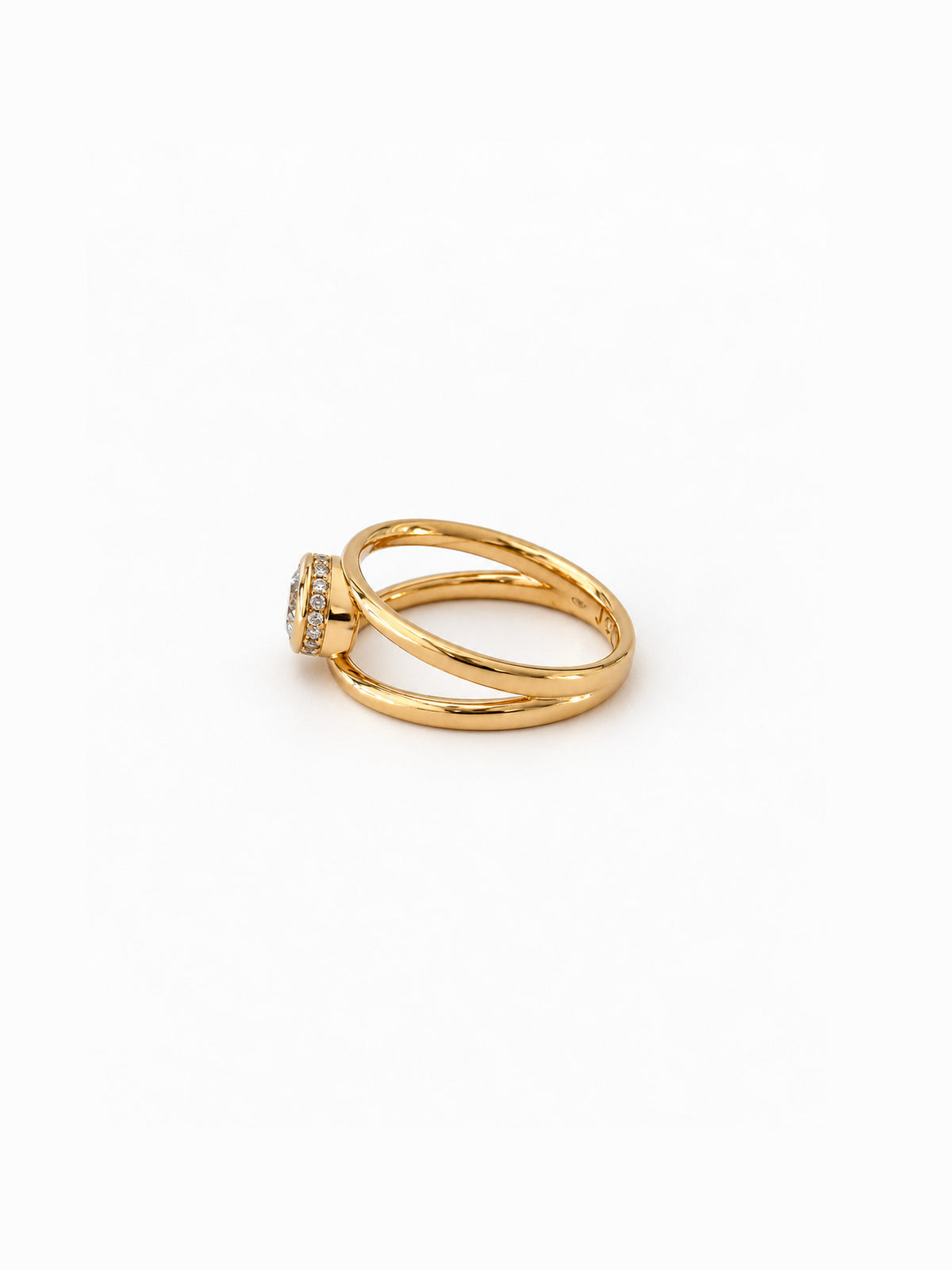 A gold ring with a double-band design and a small round clear gemstone, photographed on a clean white background.