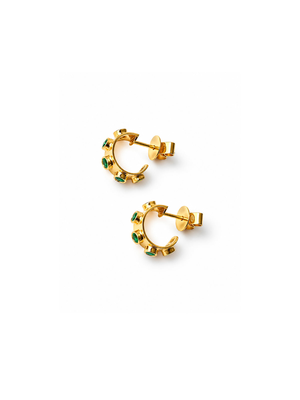 A pair of gold crescent-shaped hoop earrings with small green gemstone accents, shown on a plain white background.