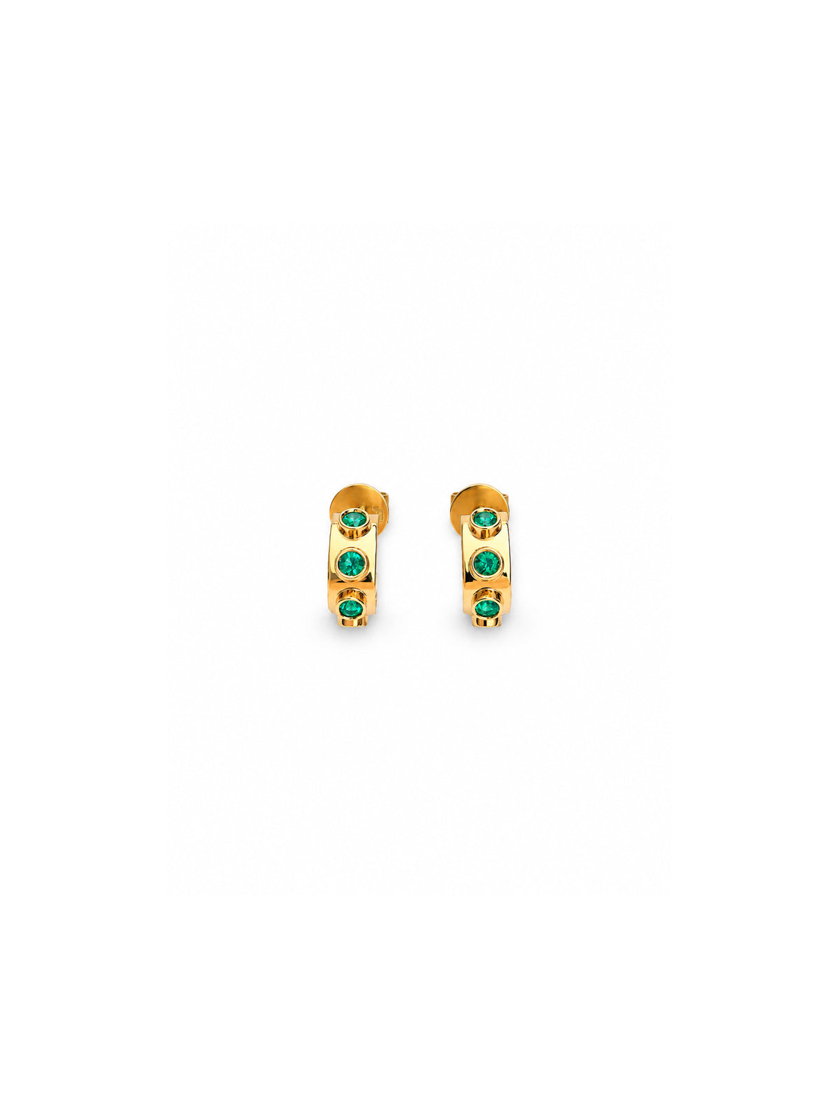 A pair of gold huggie hoop earrings, each adorned with three small round green gemstones, set against a solid white background.