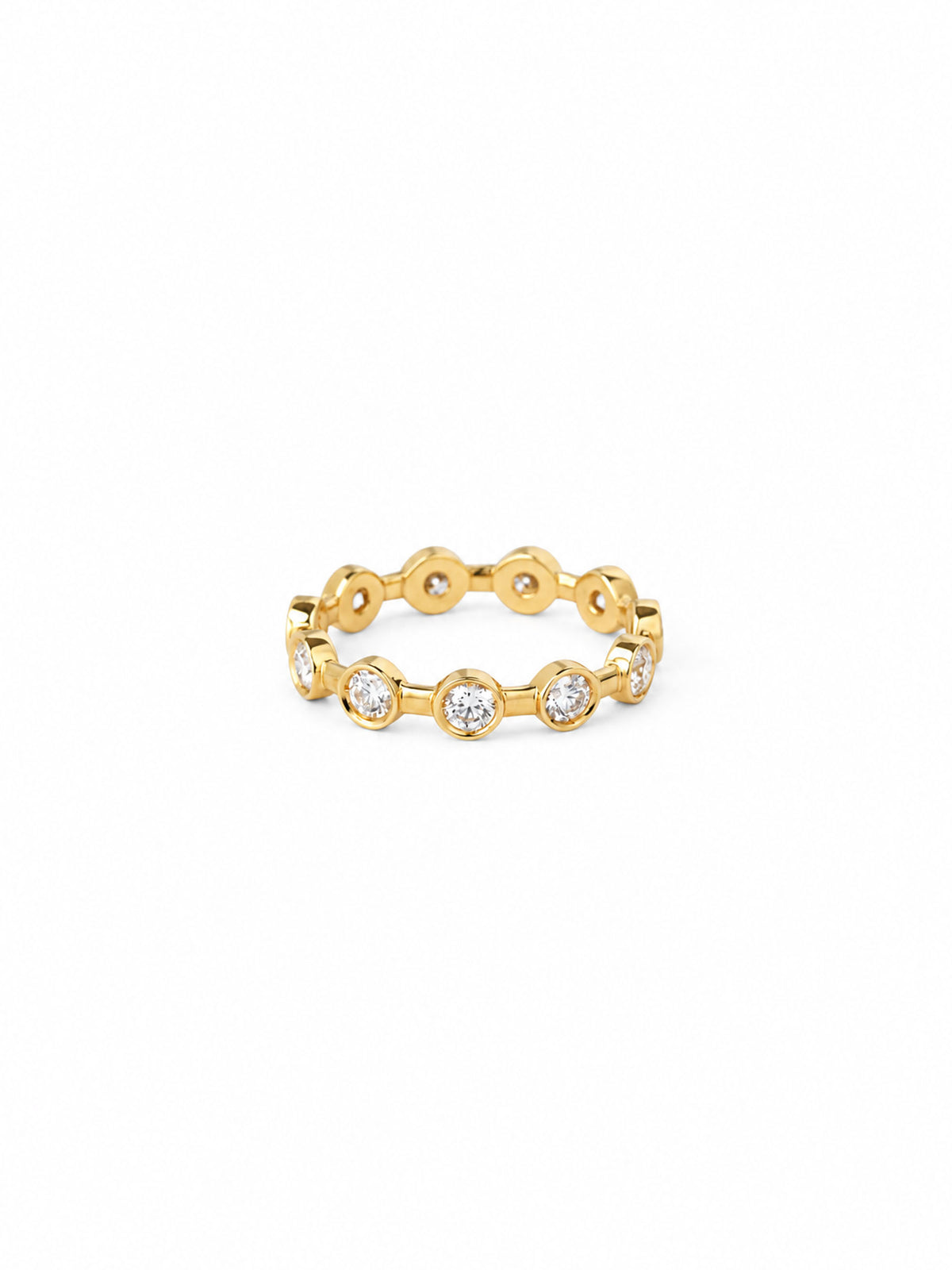 A gold eternity-style ring featuring a series of small bezel-set round clear gemstones, photographed on a clean white background.
