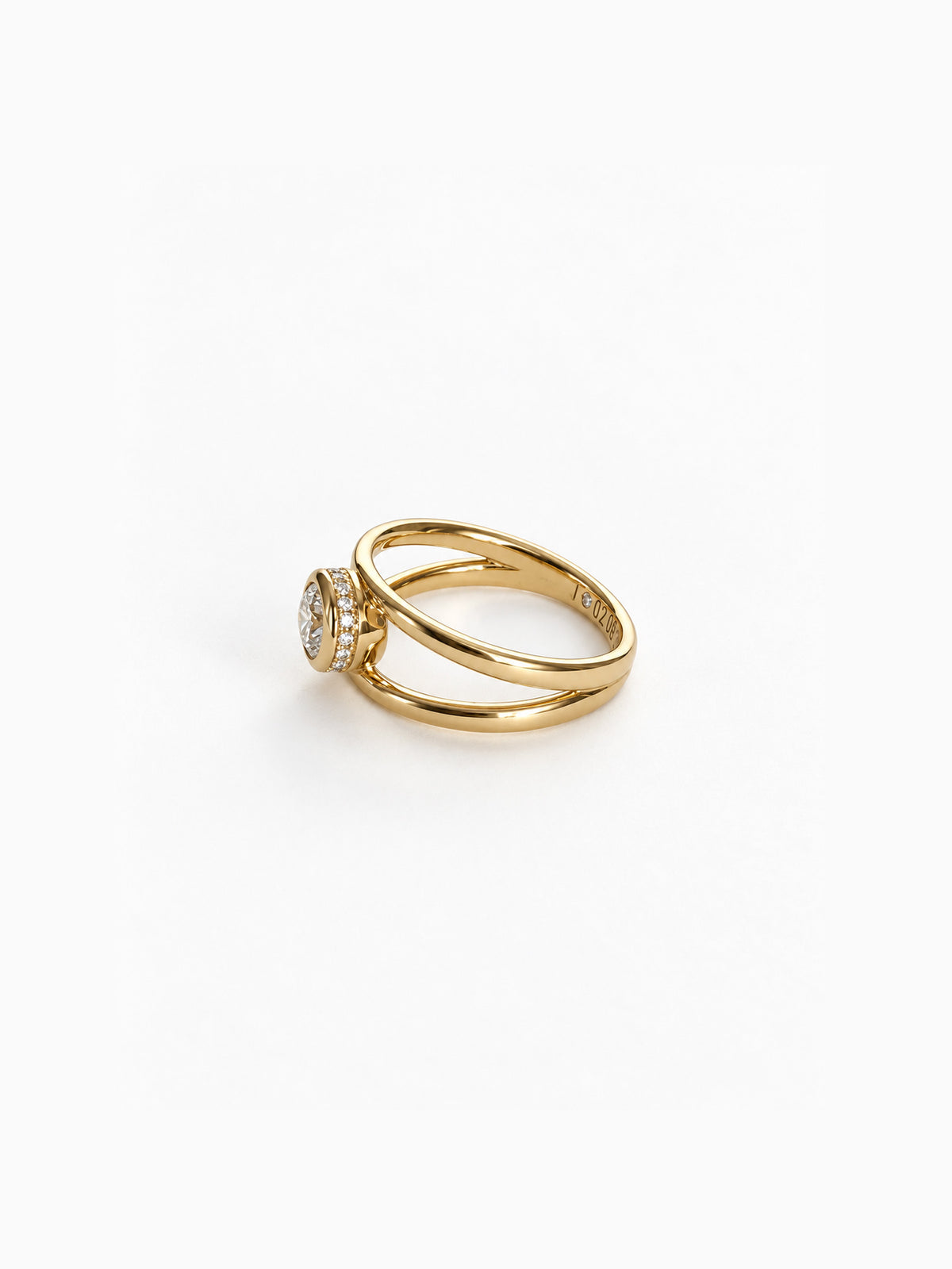 A gold ring with a double-band design and a round cluster of clear gemstones on the front, photographed on a clean white background.