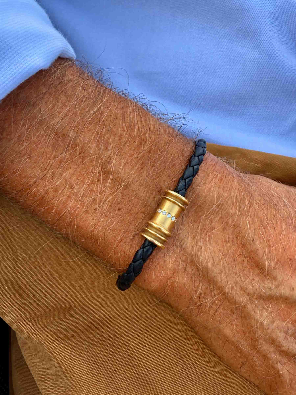 black braided leather bracelet with a gold cylindrical clasp adorned with small diamonds stones